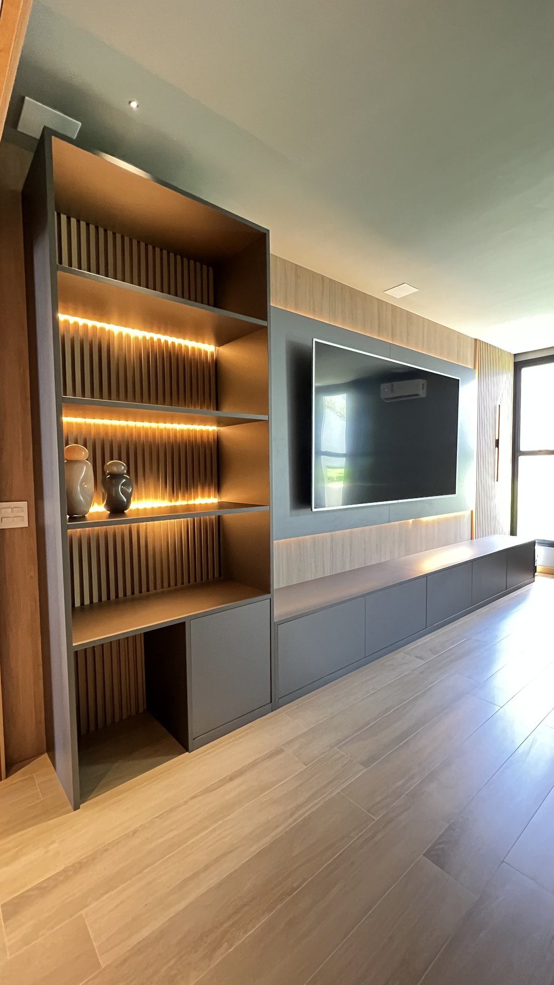 Sala de estar com estante e painel de TV planejados pela Villa